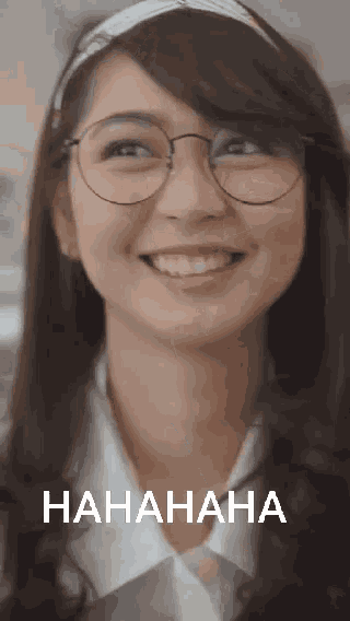 a woman wearing glasses and a headband is smiling and laughing with the word hahaha in the corner
