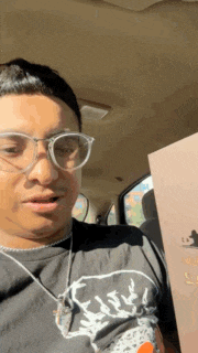 a man wearing glasses and a snoopy shirt is sitting in a car