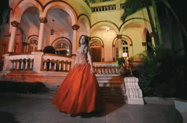 a woman in a red gown stands in front of a building