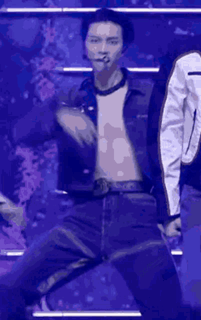 a man without a shirt is dancing on a stage with other people .