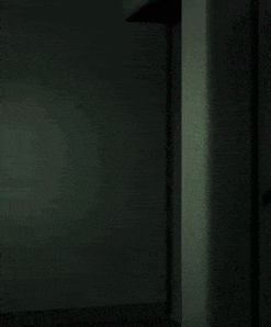a man in a suit and sunglasses is standing in a dark room