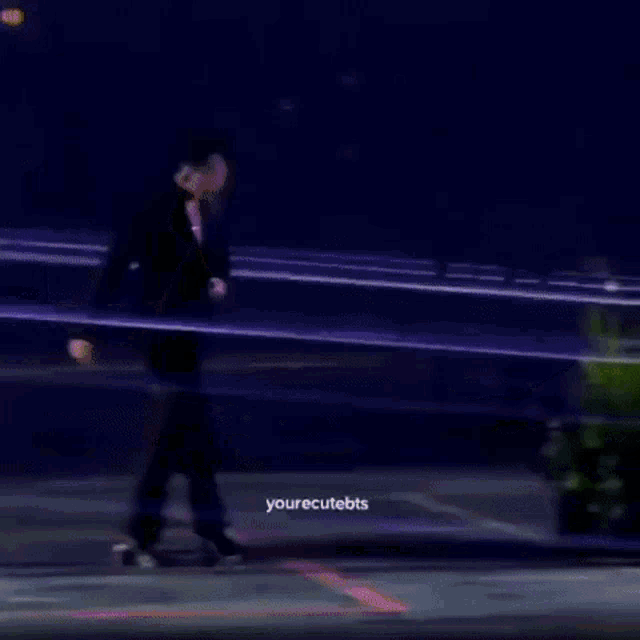 a man in a suit is walking on a stage surrounded by flowers and plants .