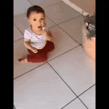 a baby is sitting on a tiled floor eating something .