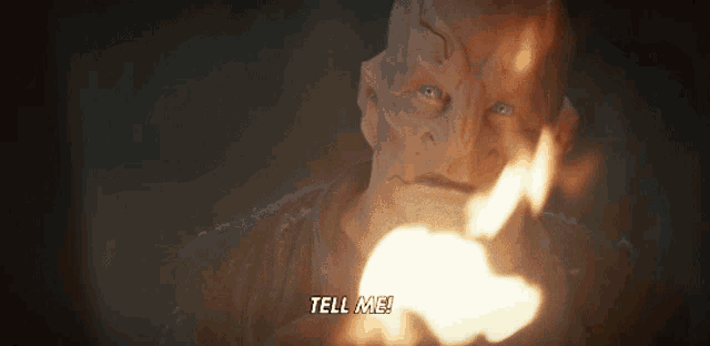a close up of a man holding a fire and the words tell me