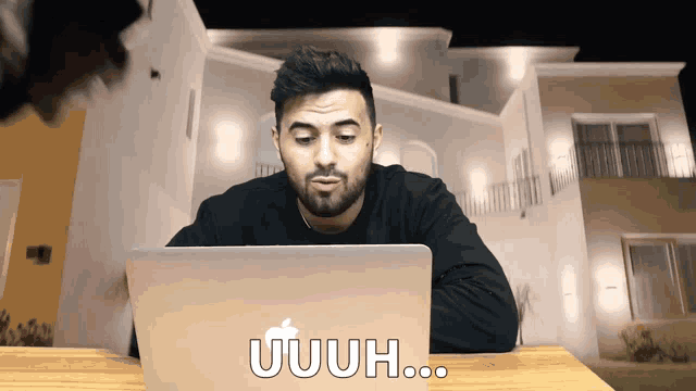 a man sitting in front of a laptop that says uuh on the screen