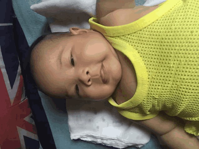 a baby in a yellow tank top is smiling