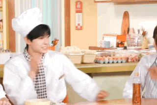 a man in a chef 's hat is sitting at a table with a woman .