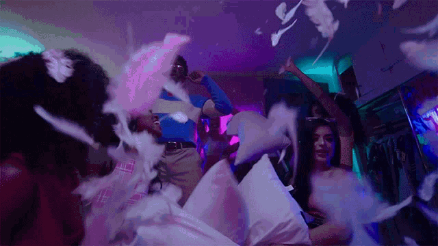 a group of people are having a pillow fight with feathers