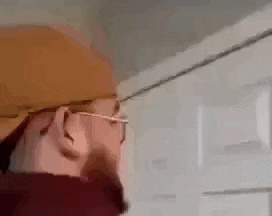 a man wearing glasses and a hat is holding a piece of cardboard in his mouth .