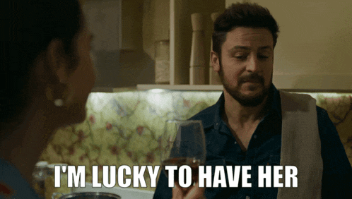 a man is holding a wine glass and says i 'm lucky to have her