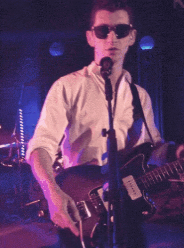 a man wearing sunglasses is playing a guitar on stage