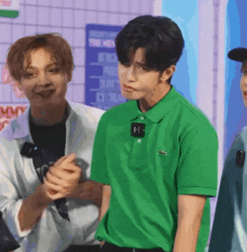 a man wearing a green lacoste polo shirt is standing next to another man