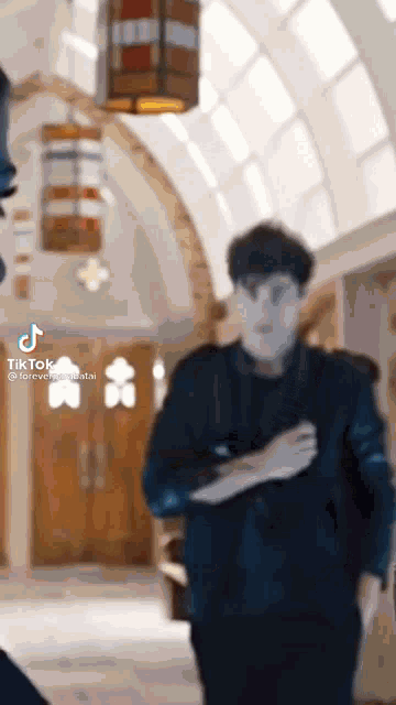 a man in a suit is walking down a hallway with a lantern hanging from the ceiling .