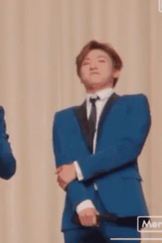 a man in a blue suit and tie is holding a microphone and dancing on a stage .