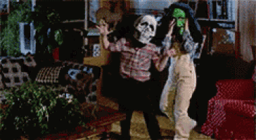 a man in a skeleton mask is dancing with a woman in a green mask
