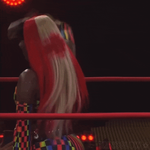 a woman with long red hair is standing in a wrestling ring