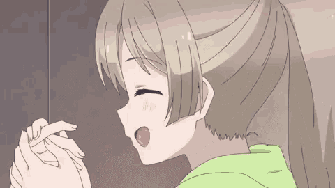 a girl in a green hoodie is making a heart with her fingers .