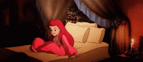 ariel from the little mermaid is sitting on a bed in a dark room .