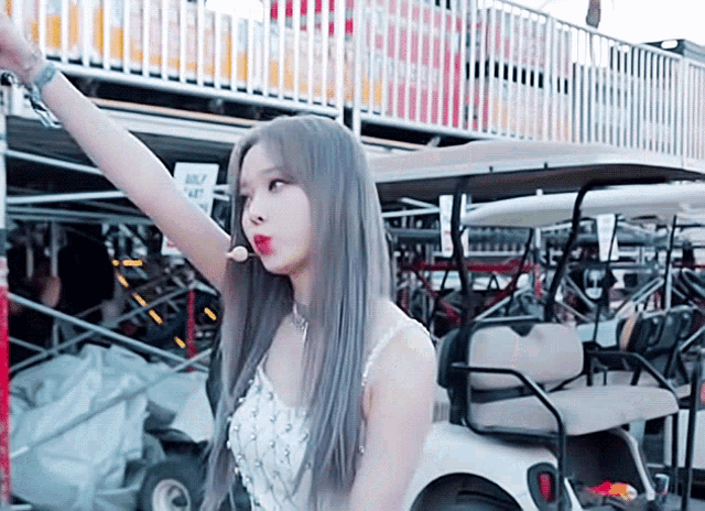 a woman sitting in a golf cart with her arm up