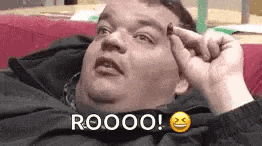 a fat man is laying on a couch with his hand on his forehead and making a funny face .