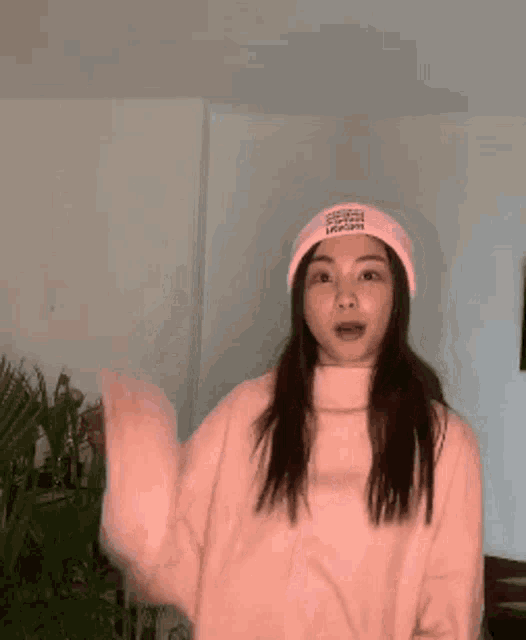 a woman wearing a pink sweater and a pink hat giving the middle finger