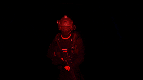a soldier with a helmet and a gun giving the middle finger in the dark