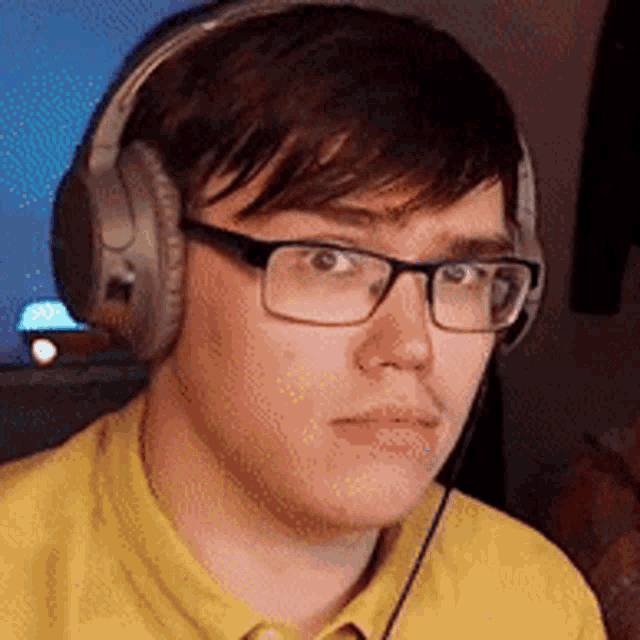a young man wearing glasses and headphones is sitting in front of a computer .
