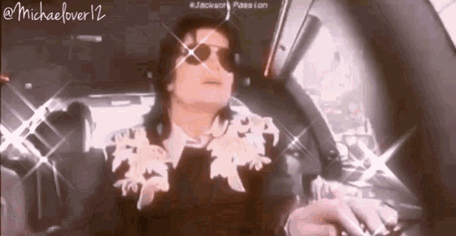 michael jackson is sitting in the back seat of a car wearing sunglasses and a black jacket .