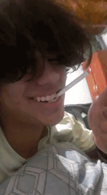a young man is smoking a cigarette and smiling while laying on a bed