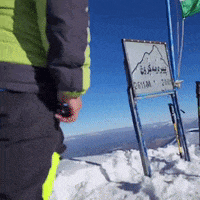 a person standing on top of a snow covered mountain next to a sign that says 2611m