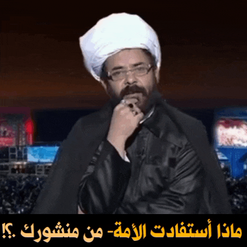 a man wearing glasses and a white turban stands in front of a sign that says ' arabic '