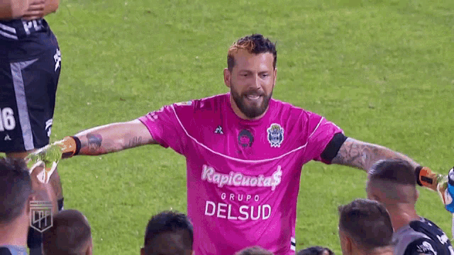 a group of soccer players are huddled around a man wearing a pink shirt that says rapid