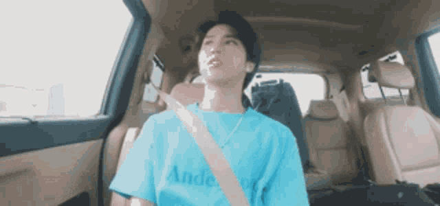 a man is sitting in the back seat of a car wearing a blue shirt that says andes .