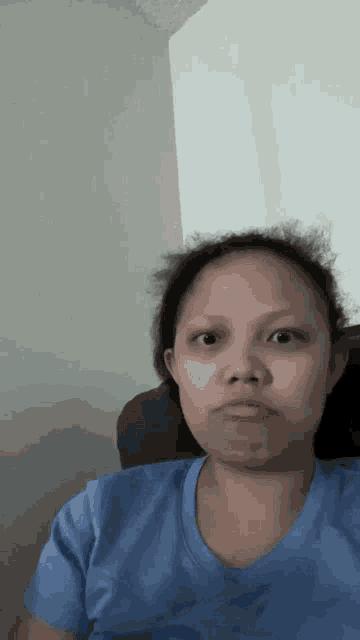 a woman in a blue shirt is sitting in a chair