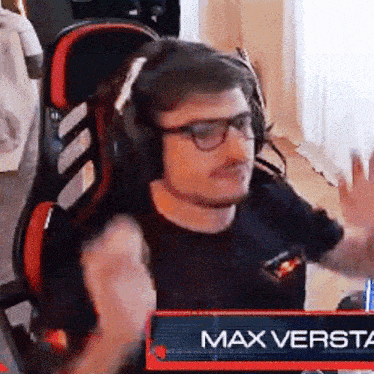 a man wearing headphones and glasses is sitting in a chair with a sign that says max versta in front of him