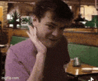 a man in a purple shirt is sitting at a table in a restaurant
