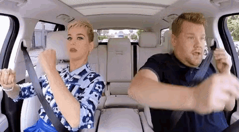 a man and a woman are sitting in the back seat of a car with their seat belts on .