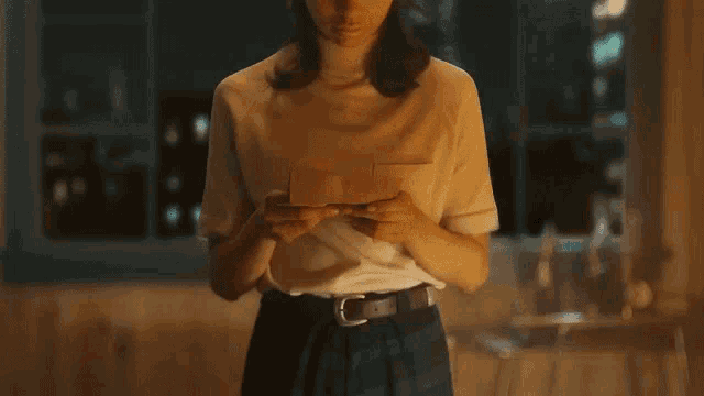 a woman is holding a piece of paper in her hands and looking at it .
