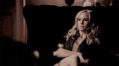 a woman is sitting in a chair in a dark room looking at the camera .