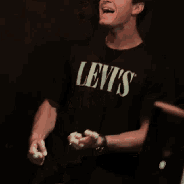 a man wearing a black levi 's t-shirt is smiling