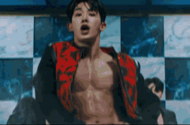 a shirtless man is dancing in front of a checkered wall