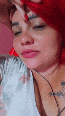 a woman with red hair and a tattoo on her chest has her hand on her forehead .