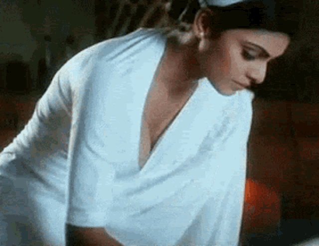 a woman in a white nurse 's uniform is kneeling down and looking down .