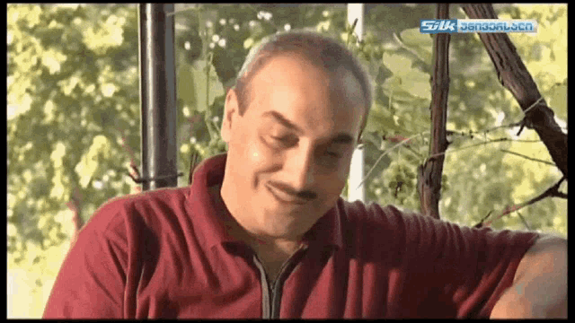 a man in a red shirt is smiling in front of a screen that says silk on it