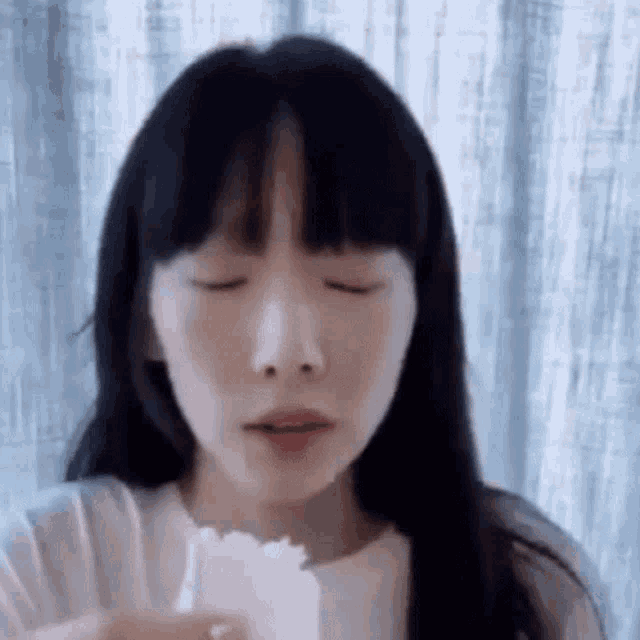 a woman with long black hair is eating a piece of bread .