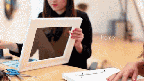 a woman is holding a picture frame and the word frame is visible in the corner