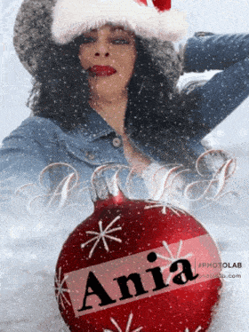 a woman in a santa hat is holding a red christmas ornament with the name ania on it