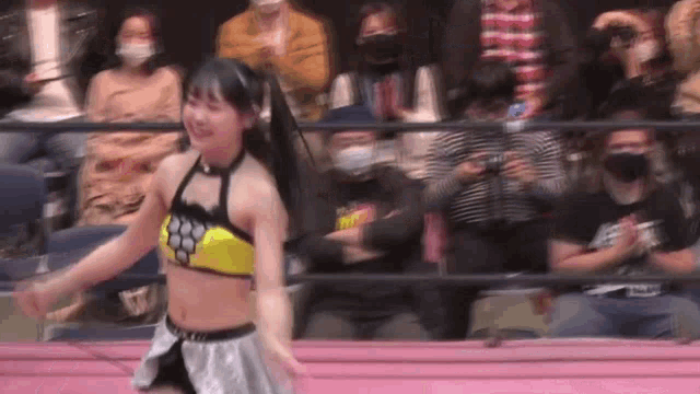 a woman is dancing in a wrestling ring in front of a crowd of people .