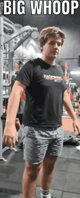 a man in a black shirt with the word radioactive on it is standing in a gym