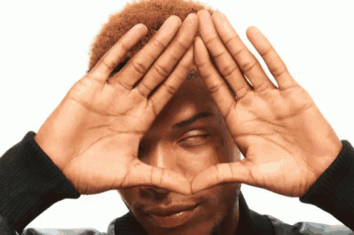 a man with a tattoo on his forehead makes a heart with his hands